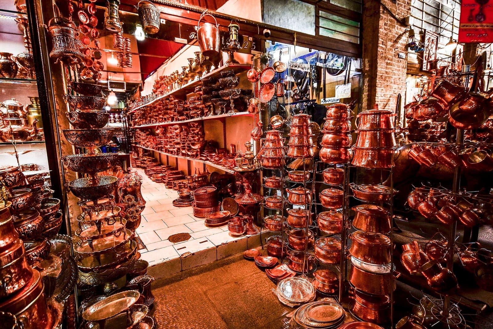 Coppersmiths' bazaar in Esfahan, stacked hand-hammered pots glowing under shop lights